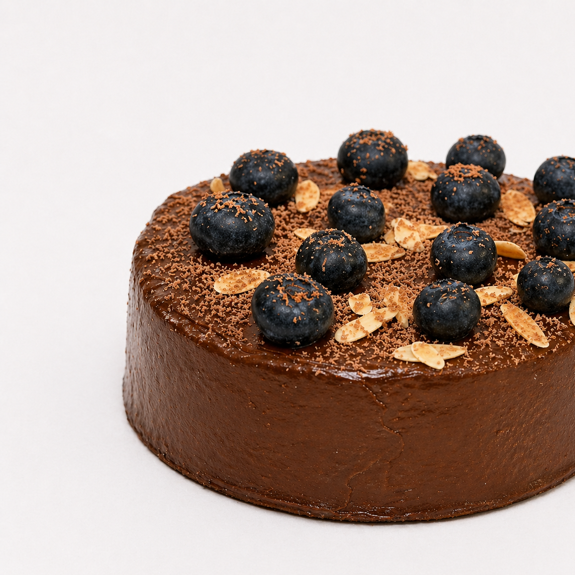 Chocolate cake with blueberries and gold leaf on a white background