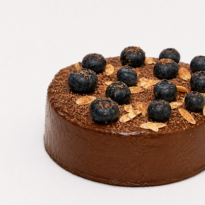 Chocolate cake with blueberries and gold leaf on a white background